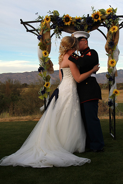 bride and groom kissing under outdoor arch